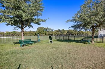 A park with benches and trees in front of a fence